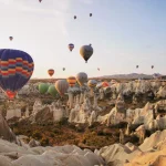 Hot air balloons rising above Cappadocia’s rocky valleys at sunrise